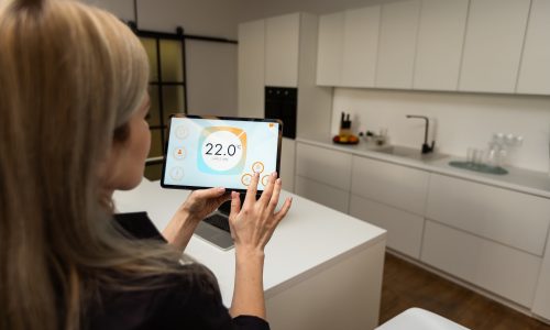 Iot Smart Home Concept - rear view of woman ask digital tablet to set temperature of air conditioner