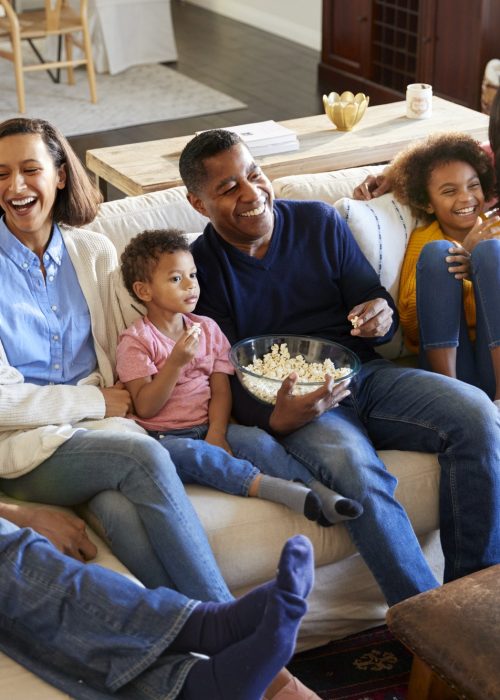 Three generation family mixed race family sitting on the sofa in living room, watching TV